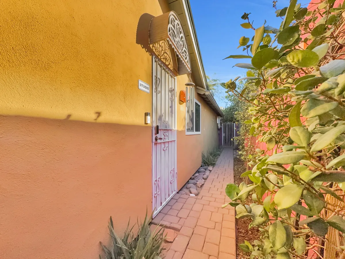 This exterior image features a decorative door gate and a pathway leading to a vibrantly colored entrance. The cheerful wall colors and inviting pathway create a sense of arrival and welcome, perfectly illustrating the private entry described in the section.