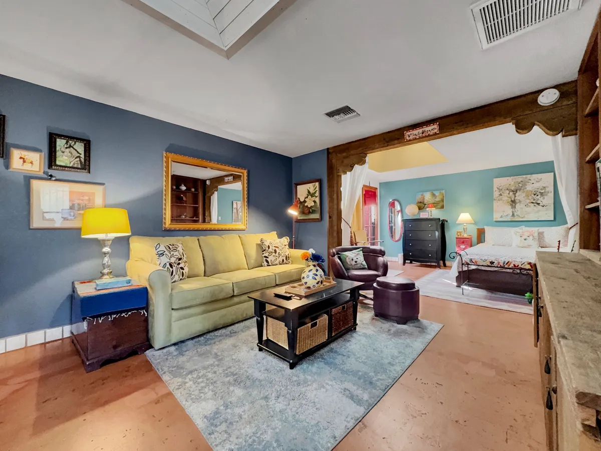 A cheerful living/lounge area centered around a green sofa and coffee table, complemented by a decorative mirror, wall art, and warm lighting. The setting is ideal for relaxing with a book, socializing, or streaming a favorite show.